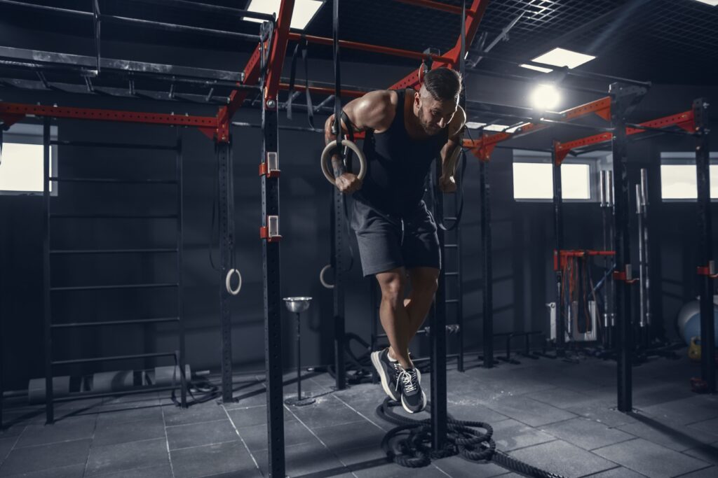 young-muscular-athlete-practicing-pull-ups-gym-with-rings